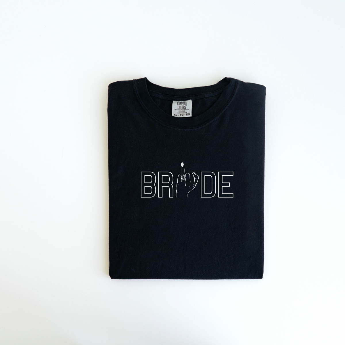 Introducing the "Bride Tee" by badd-boss-f3a0: a custom-designed black T-shirt featuring the word "BRIDE" with a bold and cheeky twist—the letter "I" is uniquely styled as a hand showing a raised middle finger. This fun and daring design, perfect as a cheeky wedding gift, is beautifully presented against a white background.