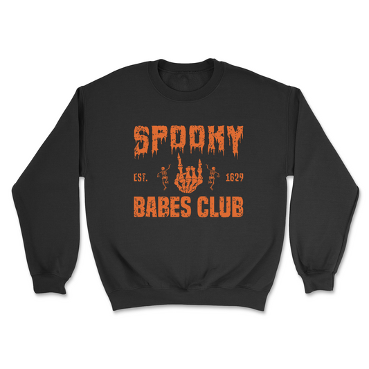 Introducing the Spooky Babe Sweatshirt & T-shirt by badd-boss-f3a0: A sleek black top featuring "SPOOKY BABES CLUB" in an eerie, orange dripping font. Between "SPOOKY" and "BABES CLUB," an illustration of skeleton hands forming a heart adds a touch of macabre charm. Flanking the illustration is “Est. 1629,” making it the perfect piece for any Spooky Babe.