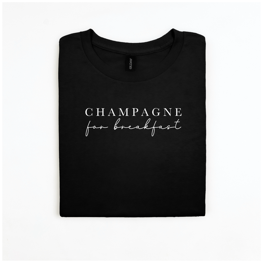 Here's a description rewritten using the given product data:

The "Champagne For Breakfast Tee" from badd-boss-f3a0 features a neatly folded black design made from 100% cotton, providing a plush and breathable experience. It showcases the phrase "CHAMPAGNE for breakfast" printed in elegant white cursive and serif fonts. This Gildan Softstyle tee offers a unisex fit and is beautifully displayed against a plain white background.
